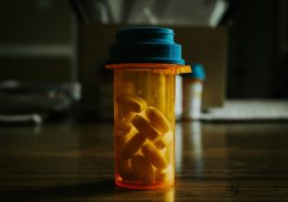 A prescription bottle filled with pills against a dimly lit background.